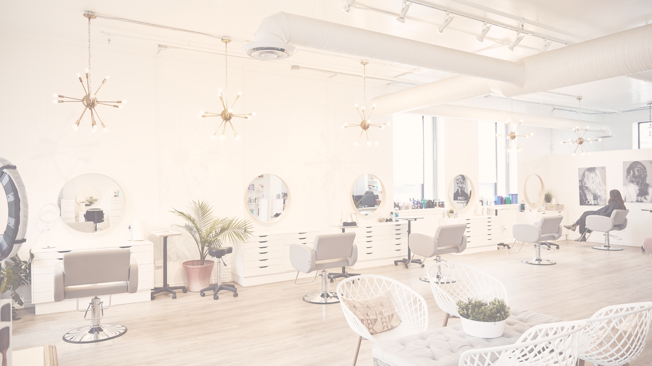 Salon chairs line a bright white wall at Luxe Beauty Company. 
