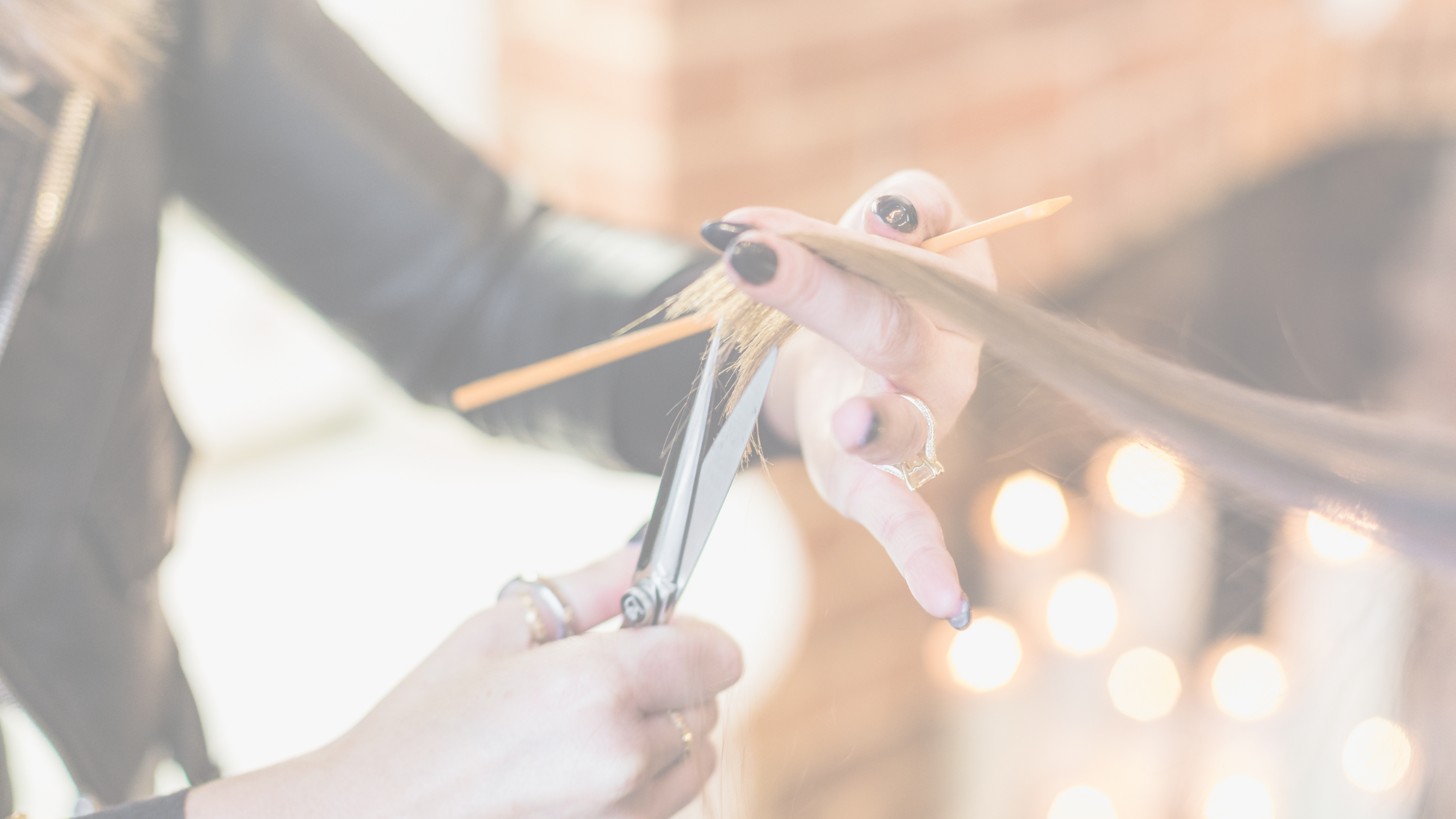 Close up of stylist cutting hair at Luxe Beauty Company. 